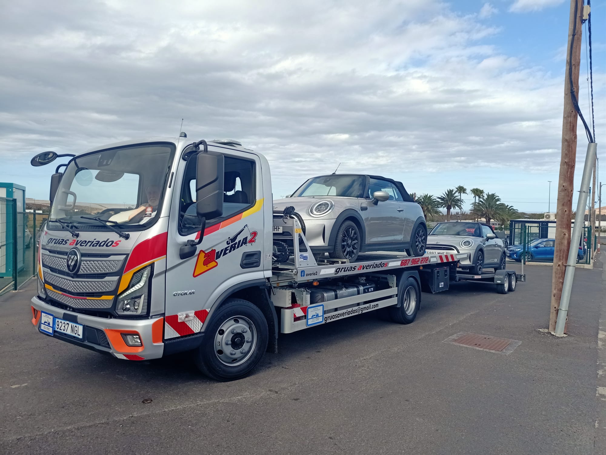 Grúa de Averiados con doble remolque transportando dos Mini descapotables
