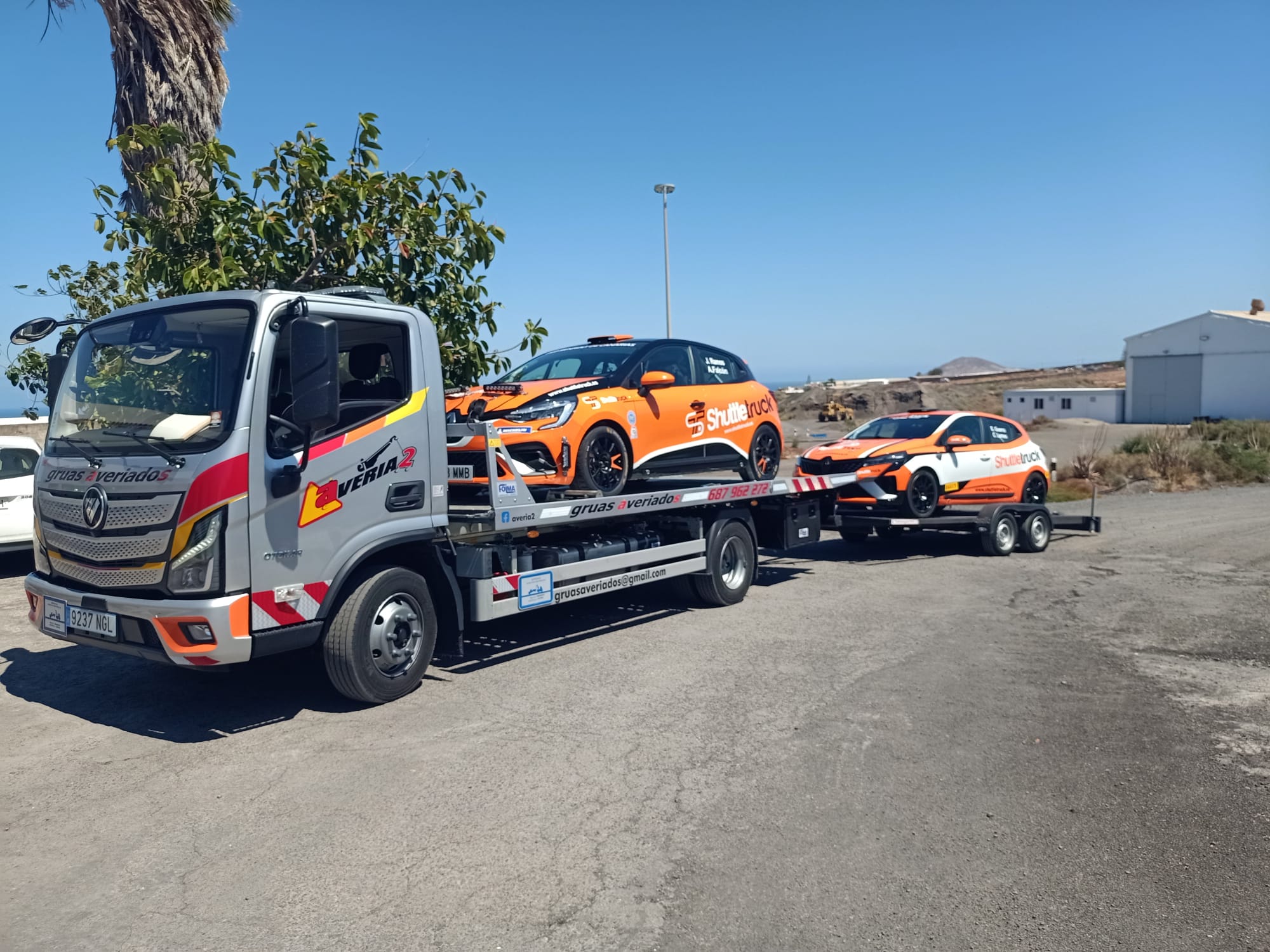Grúa de Averiados transportando dos coches de rally naranjas Shuttletruck