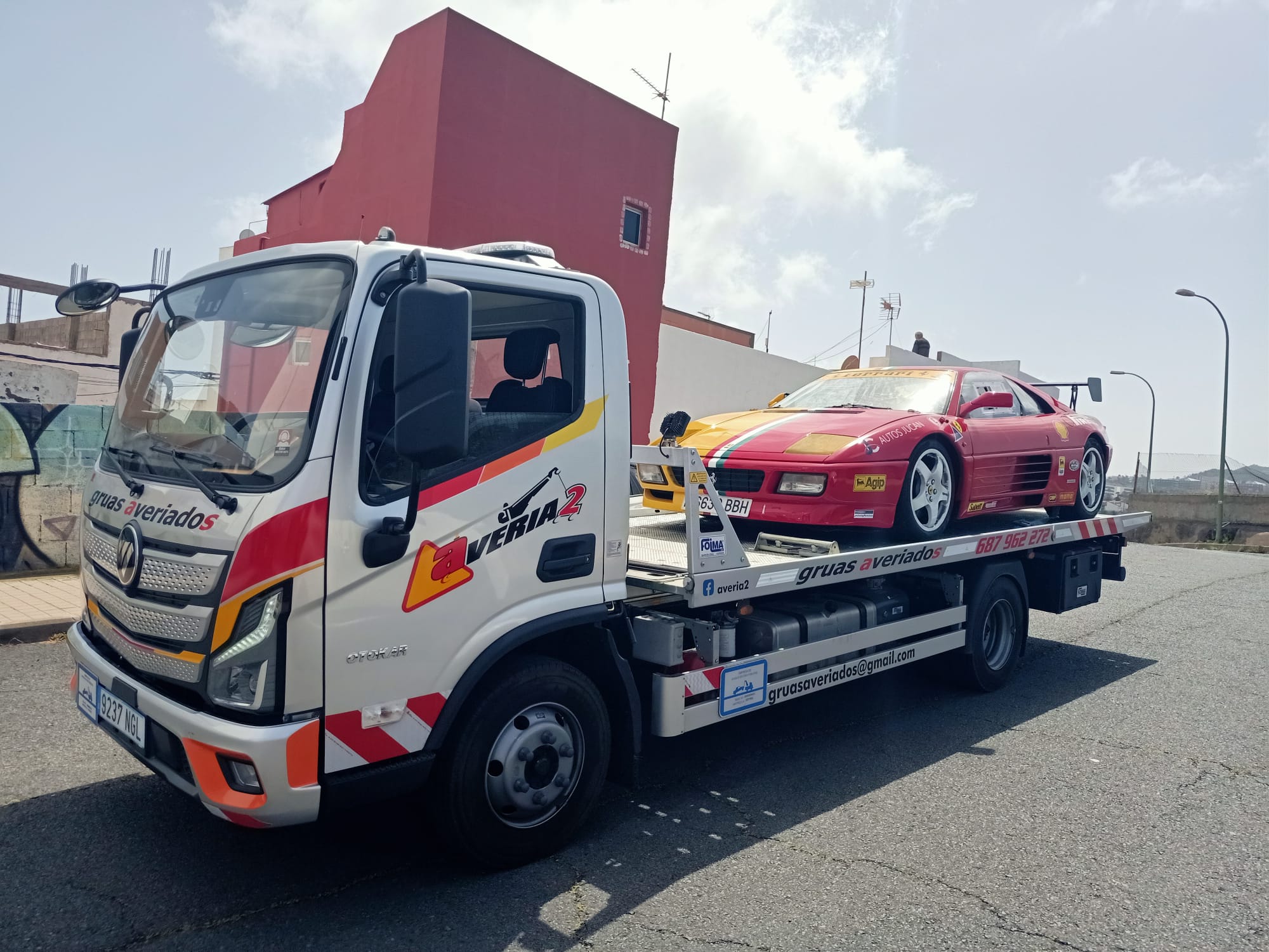 Grúa transportando un coche deportivo rojo tuneado