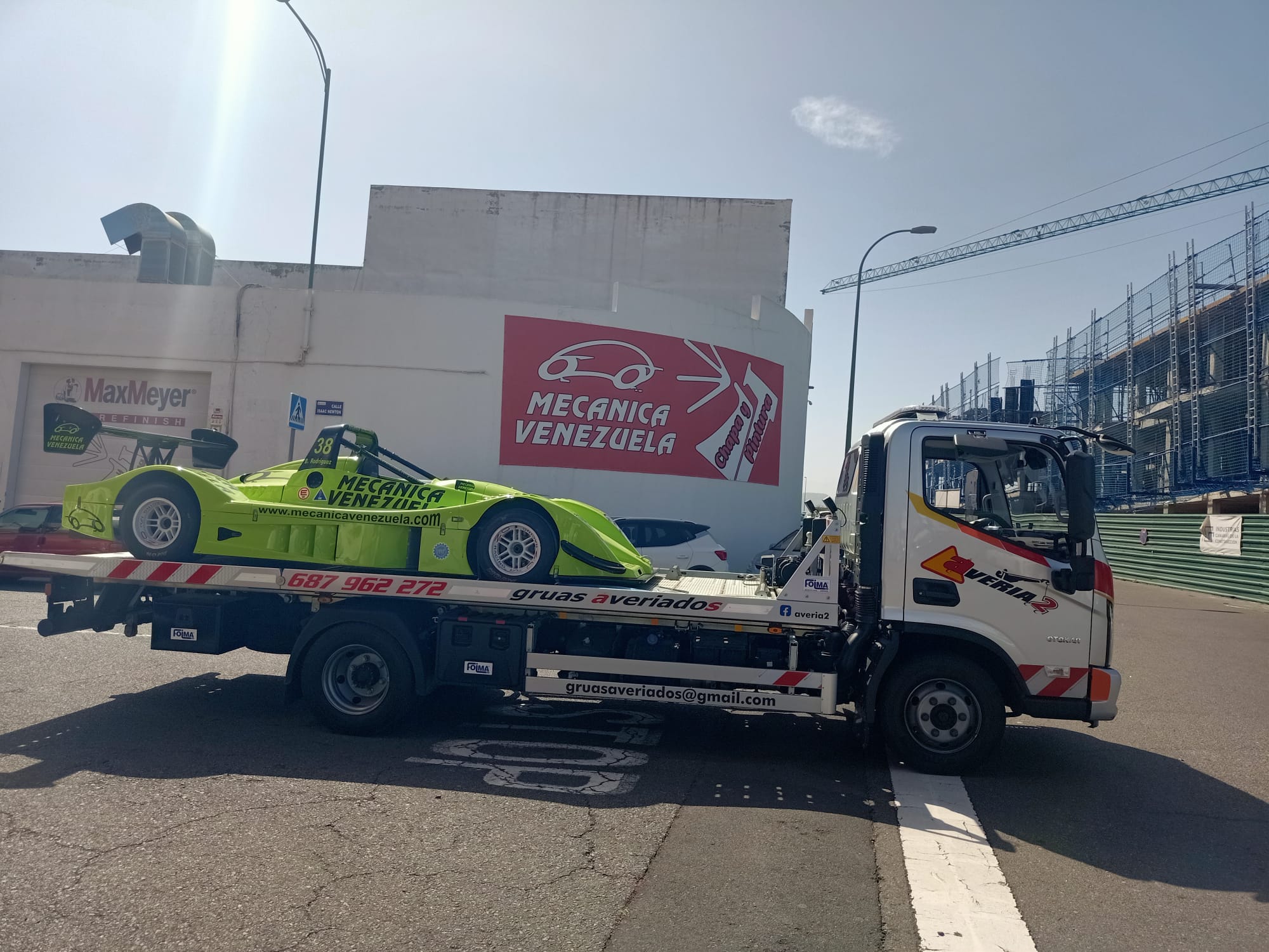 Grúa transportando un prototipo de competición verde muy bajo
